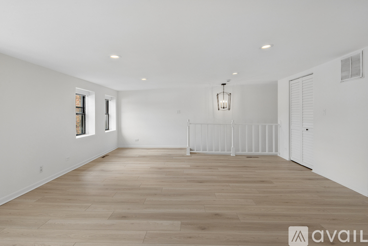 A spacious room with wooden flooring and white walls.