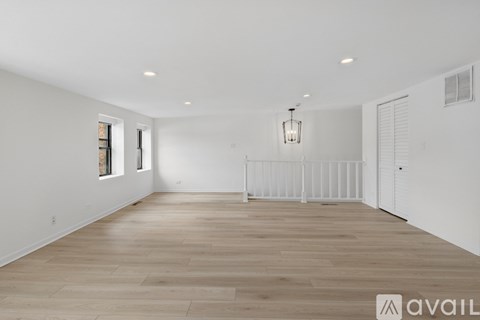 A spacious room with wooden flooring and white walls.