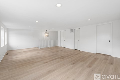 A spacious room with wooden flooring and white walls.
