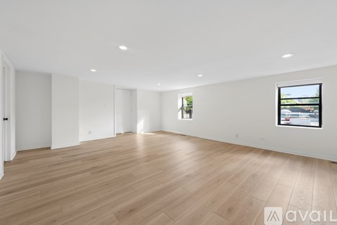 A spacious room with wooden flooring and a television mounted on the wall.