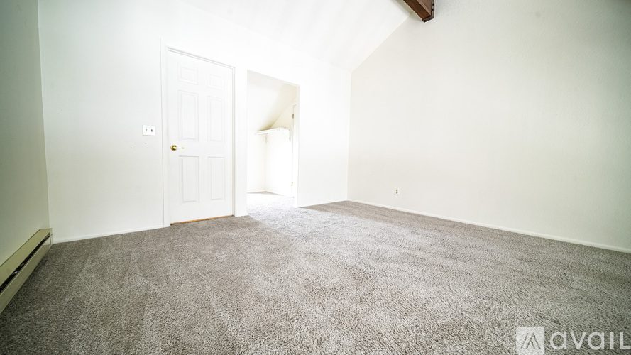 A room with a carpeted floor and a doorway leading to another room.