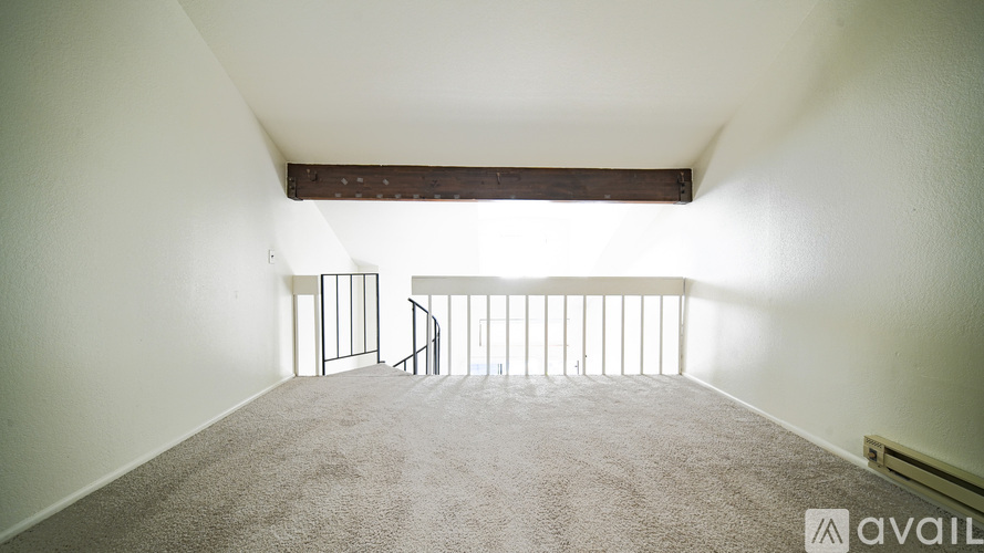 A room with a carpeted floor and a balcony with a railing.