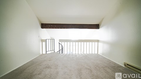 A room with a carpeted floor and a balcony with a railing.