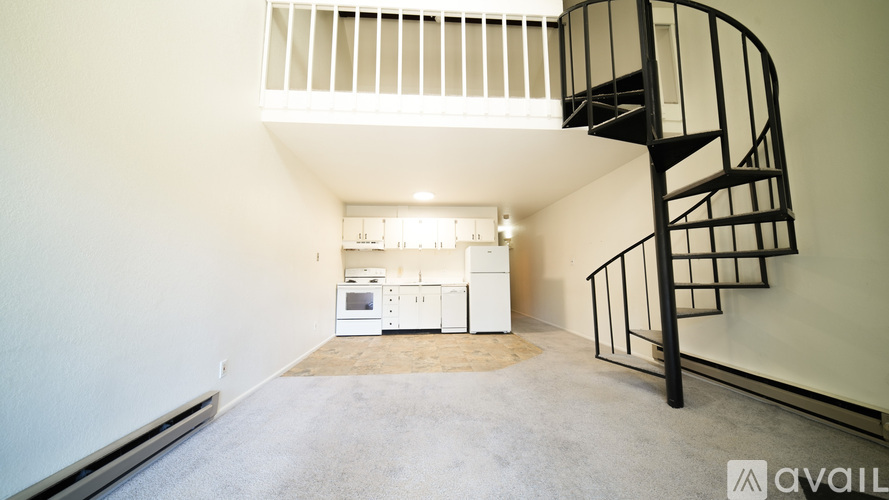 A spiral staircase in a room with a kitchen in the background.