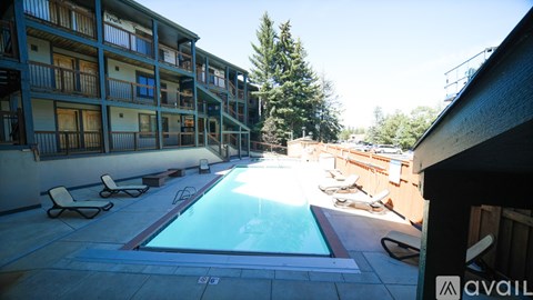 A pool area with sun loungers and a building in the background.