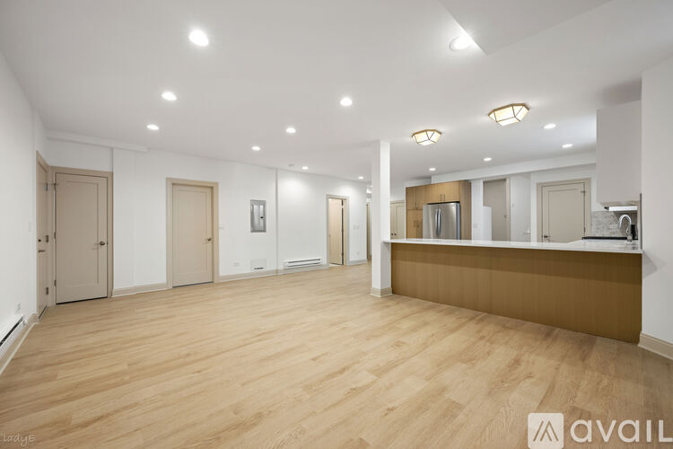 A spacious room with wooden flooring and white walls.