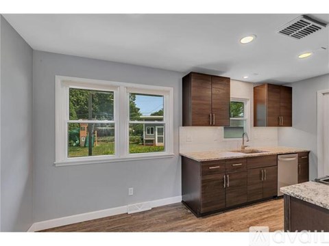 A kitchen with brown cabinets and a window overlooking a green area.