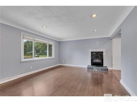A spacious room with a fireplace and a window.