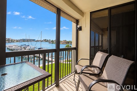 A balcony with chairs and a table overlooking a marina.