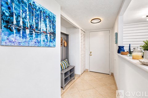 A hallway with a painting on the wall and a bench with a striped pillow.