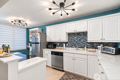 A kitchen with white cabinets and a blue backsplash.