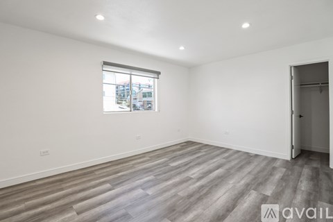 A room with wooden flooring and a window showing a view of buildings outside.