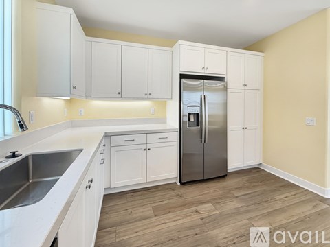 A kitchen with white cabinets and a stainless steel refrigerator.