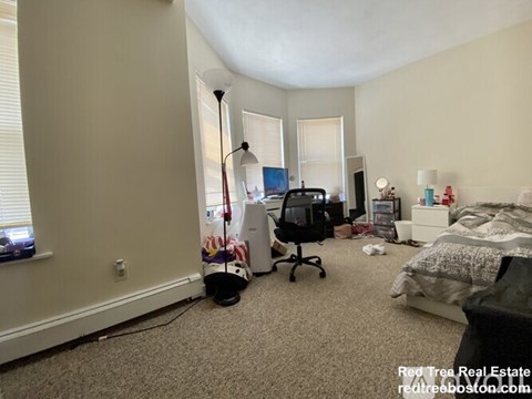A room with a bed, a desk, and a chair.