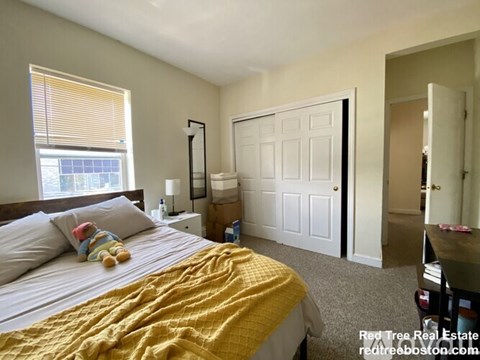 A bedroom with a bed, nightstand, and closet.