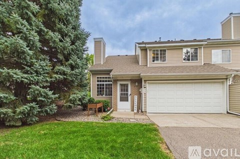 A house with a garage and a tree in front.