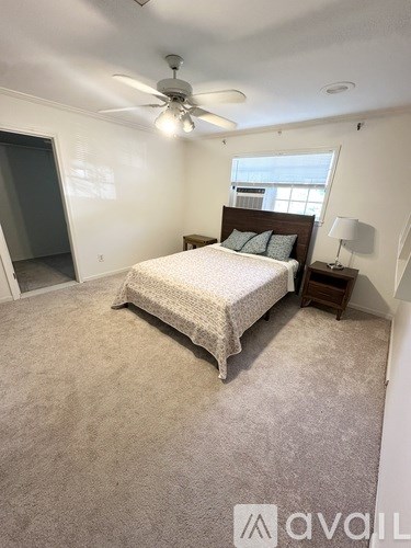 A bedroom with a bed, a ceiling fan, and a window.