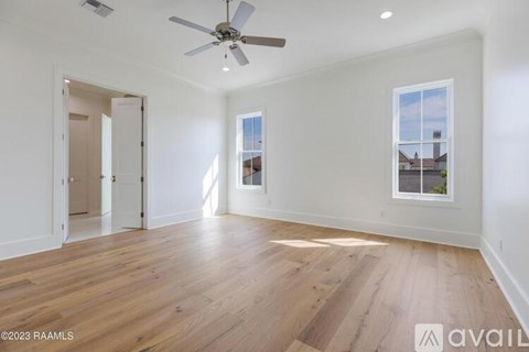 A spacious room with wooden flooring and a ceiling fan.
