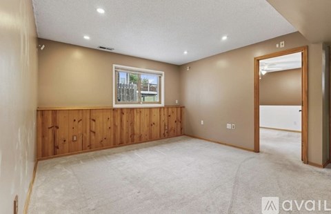 A spacious room with a window and a door on the right side.