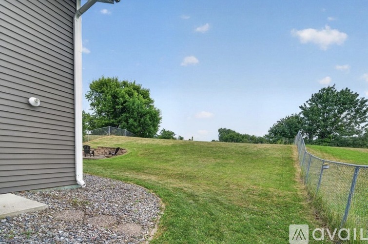 A grassy field with a fence and trees in the distance.