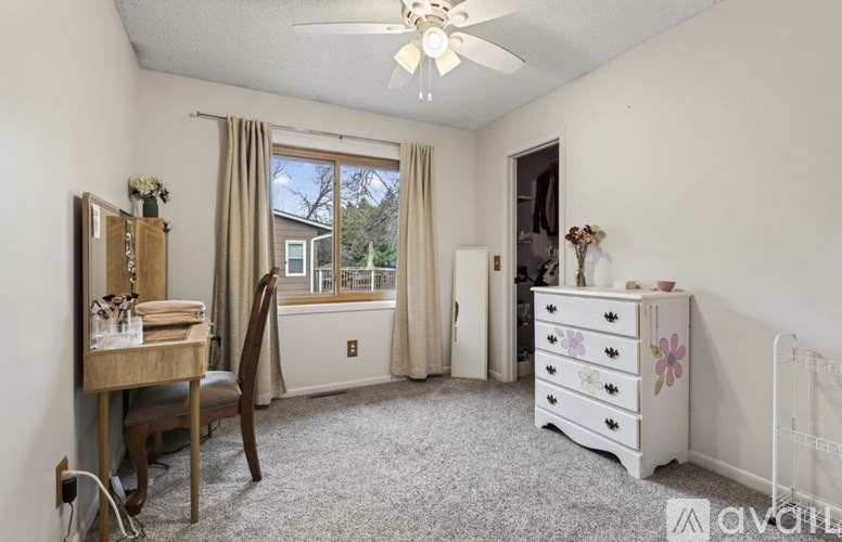 A bedroom with a white dresser and a window with curtains.