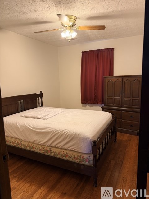 A bedroom with a bed, dresser, and ceiling fan.