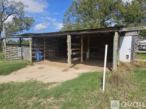 A barn with a blue container in front of it.
