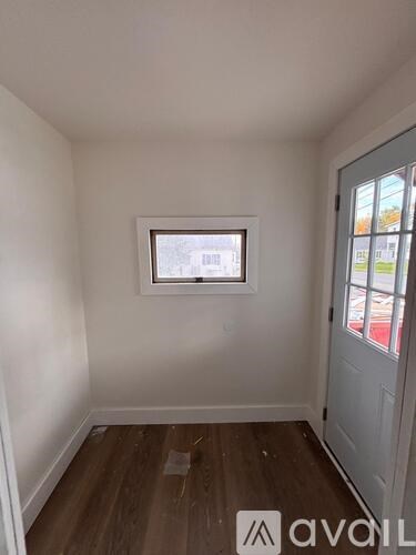 A room with a window and wooden flooring.