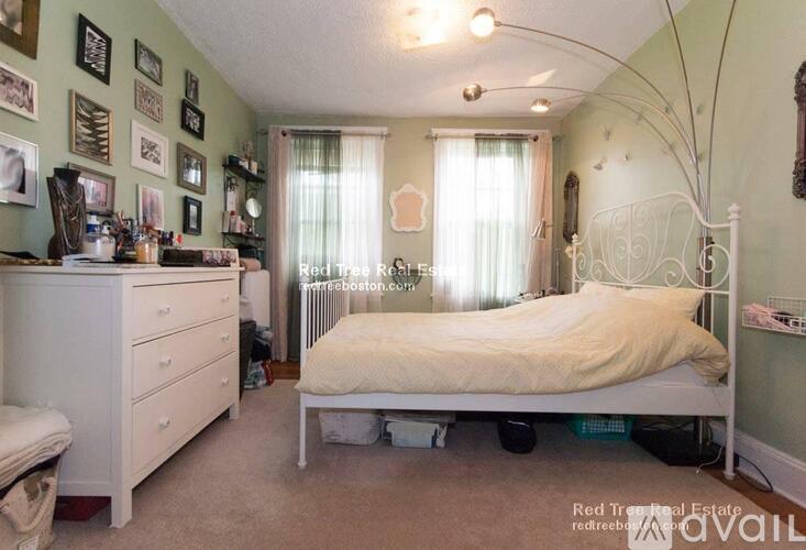 A bedroom with a white bed and a white dresser with a mirror above it.