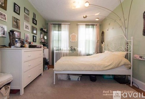 A bedroom with a white bed and a white dresser with a mirror above it.