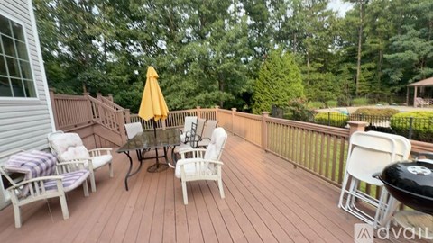 A wooden deck with a table, chairs, and an umbrella.