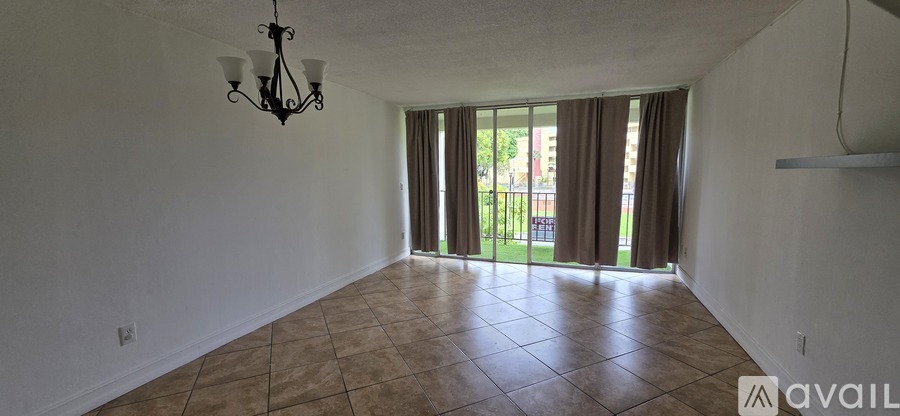 A large empty room with tiled flooring and a chandelier hanging from the ceiling.