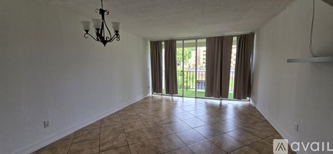 A large empty room with tiled flooring and a chandelier hanging from the ceiling.