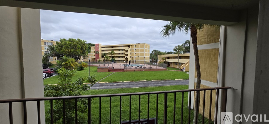 A view from a balcony looking out at a courtyard with a building in the background.