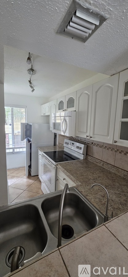 A kitchen with white cabinets and a stainless steel sink.