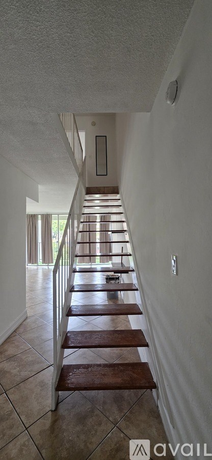 A long hallway with a tiled floor and a staircase.