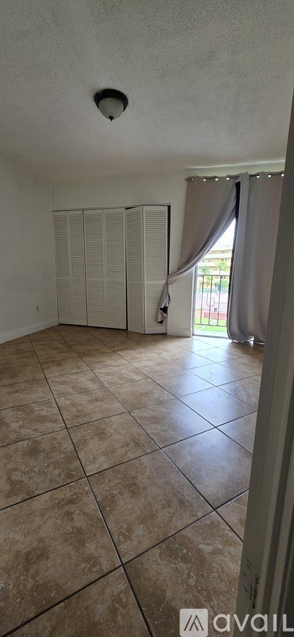 A room with a tiled floor and a window with curtains.