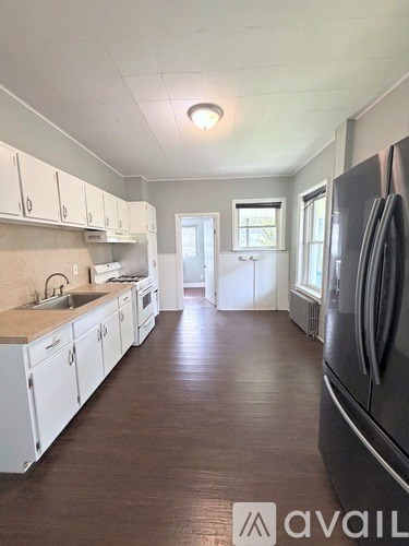 A kitchen with white cabinets and a black refrigerator.