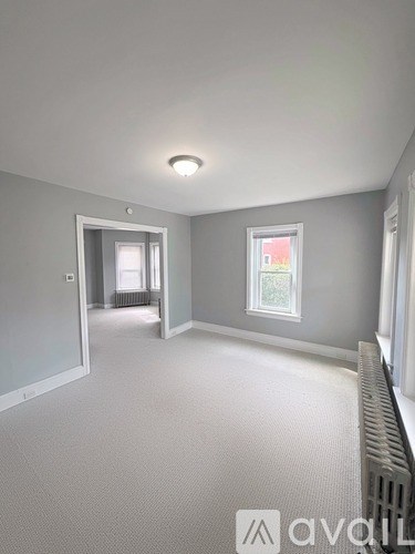 A room with a carpeted floor and a window with a view of a red building.