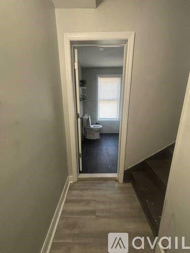 A bathroom with a toilet and sink is visible through an open door.