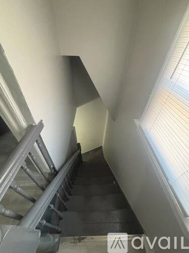 A staircase with a metal railing and a window on the side.