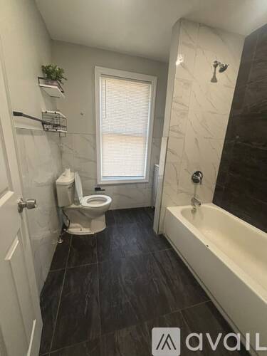 A bathroom with a toilet, tub, and window.