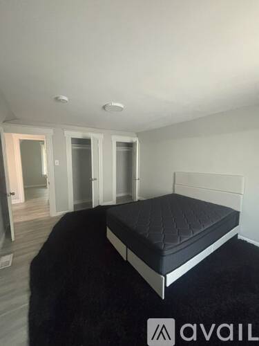A bedroom with a bed, a rug, and a wall-mounted light fixture.