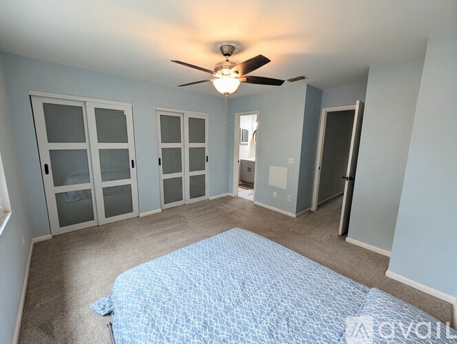 A bedroom with a bed and a ceiling fan.