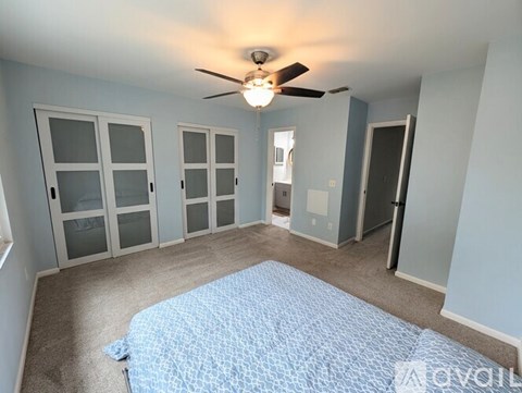 A bedroom with a bed and a ceiling fan.