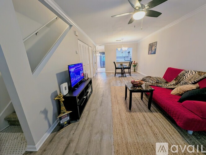A living room with a red couch and a television on a black stand.