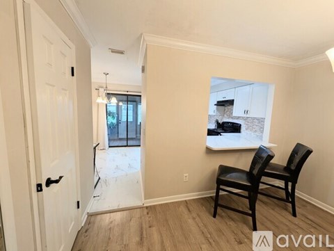 A room with a white door, two chairs and a picture on the wall.