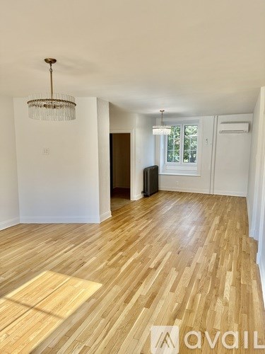 A room with wooden flooring and a chandelier hanging from the ceiling.