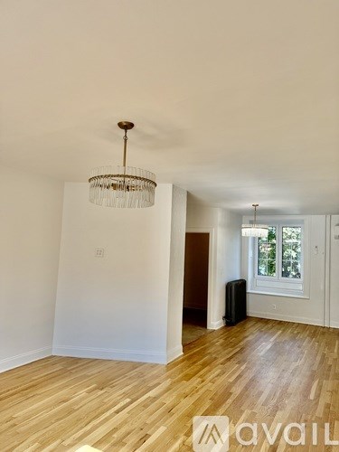 A room with wooden floors and a chandelier hanging from the ceiling.