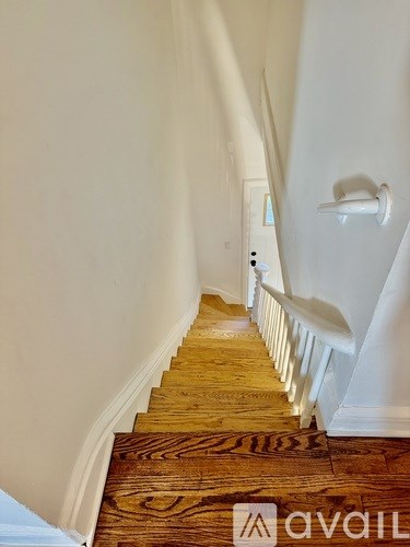 A wooden staircase with a white banister and a wooden floor.